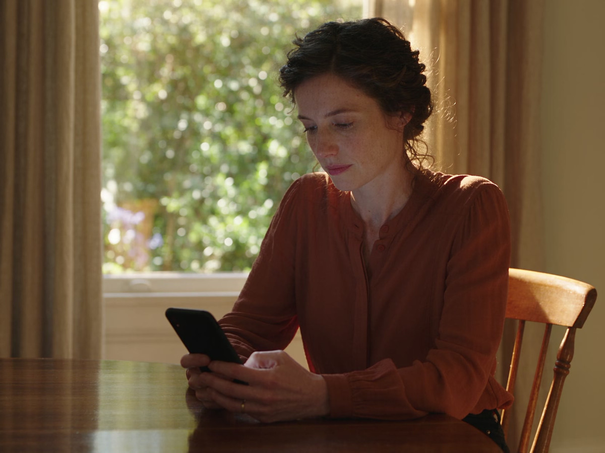 A woman at home thoughtfully chooses a gift on her phone