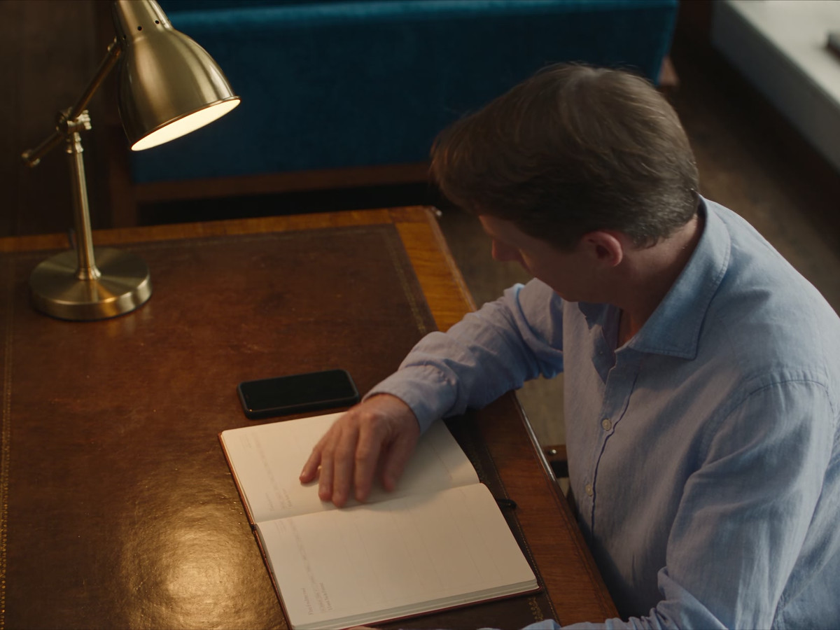 A man checks his diary, then picks up his phone.