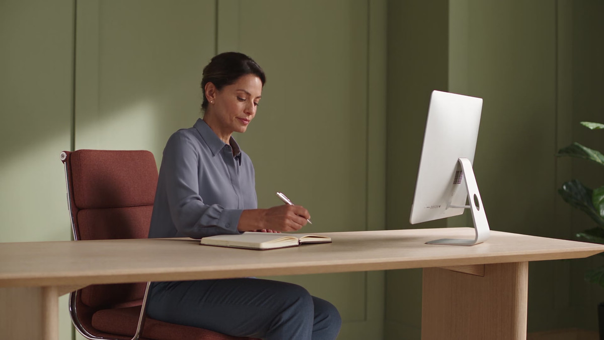 A clinic director reviews her computer and makes a note in a private office.