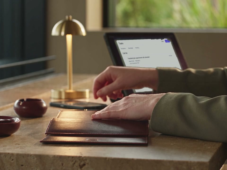 A coordinator prepares a notebook beside the patient follow-up task list