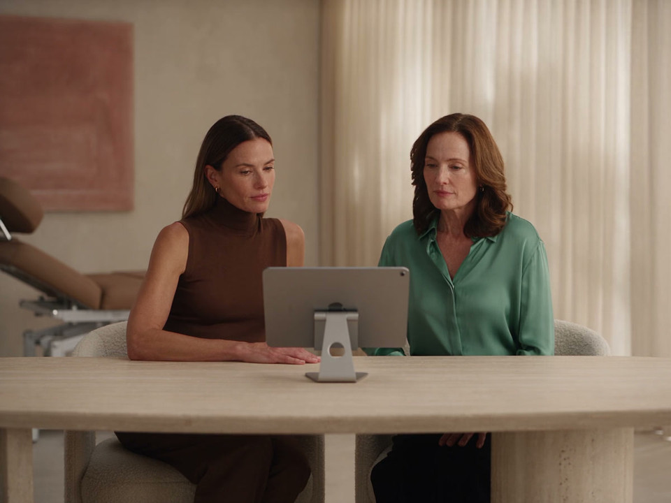 A practitioner and patient reviewing an iPad together in a contemporary consultation room.