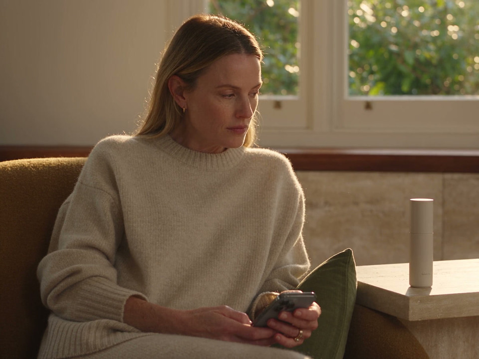A patient looks at a phone at home, with the display facing away