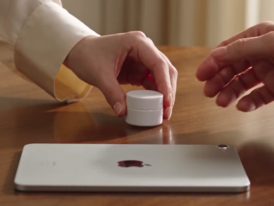 Illustrative footage of a practitioner handing a skincare sample to a patient beside an iPad.