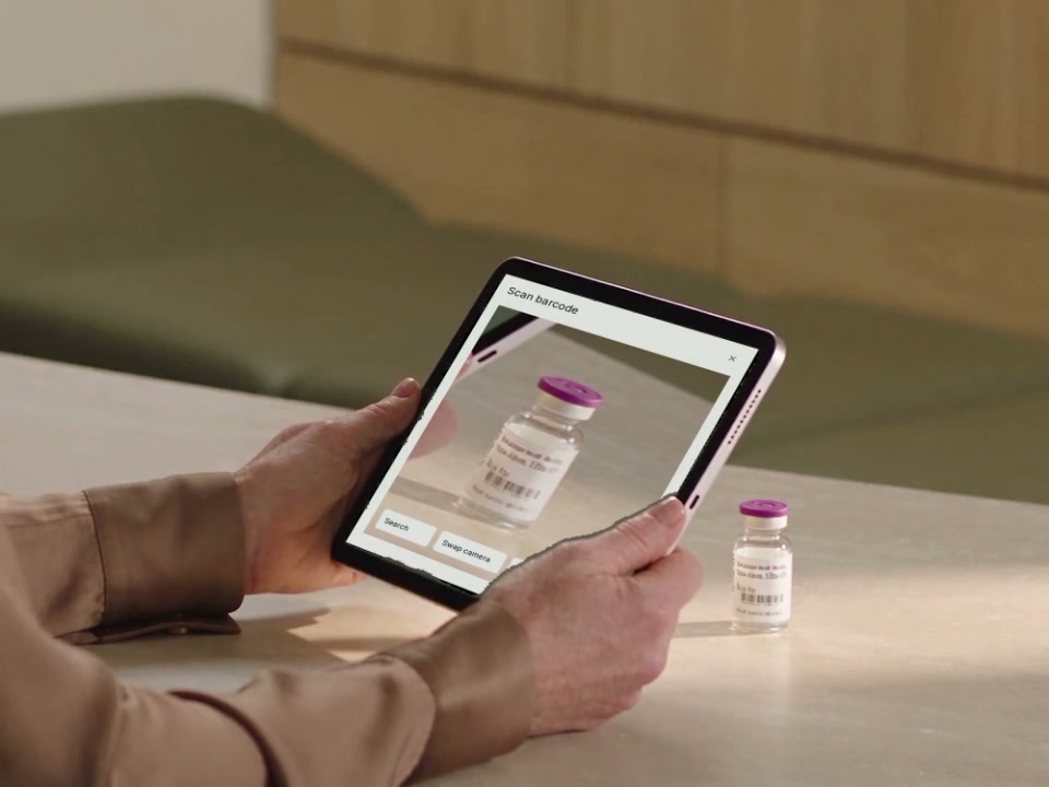 A clinician using a supported iPad beside a medicine vial on the treatment-room bench.